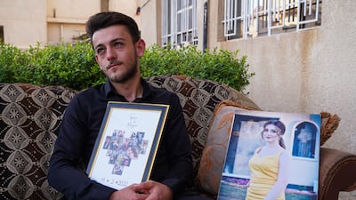 Steven Nabil, the fiance of Maryam Moatasem who died in the wedding hall fire, holds a memorial plaque containing pictures of the couple during their engagement, at his family home in Qaraqosh, northern Iraq.