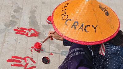 A protester paints the symbols of the three-finger salute on the ground with red paint as part of a "bleeding strike" demonstration against the military coup in Shwebo in Myanmar's Sagaing region. AFP