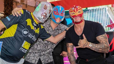 The masked wrestler poses with fans at the event.
