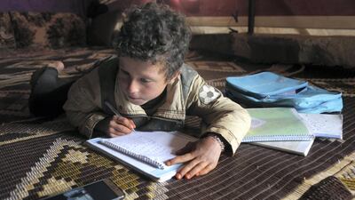A young pupil follows a lesson on a mobile telephone inside a tent, in a camp for displaced Syrians in the village of Kafr Yahmoul in the northwestern Idlib province, amid the coronavirus pandemic on April 3, 2020. - Like in much of the world, educators in Syria are taking classes online after the country's various regions sent pupils home hoping to stem the COVID-19 pandemic. But distance learning is no small feat in a country battered by nine years of war, where fighting has displaced millions and the electricity supply is sporadic at best. (Photo by Aref TAMMAWI / AFP)