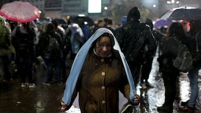 A woman covers herself with an Argentine flag under the pouring rain.