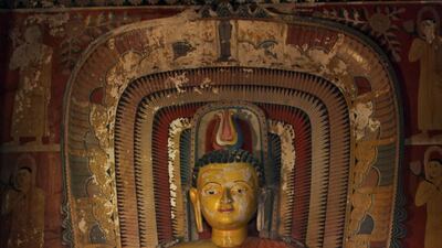 A saffron robed Sri Lankan 'samanera' or novice monk places offerings at the foot of an ancient Buddha image at a temple at Heiyanthuduwa in Biyagama. EPA / M.A.PUSHPA KUMARA