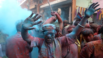 Powdered dyes are thrown by people at each other. EPA