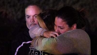 A woman who fled the Borderline Bar and Grill where a gunman injured 11 people is hugged by relatives. EPA