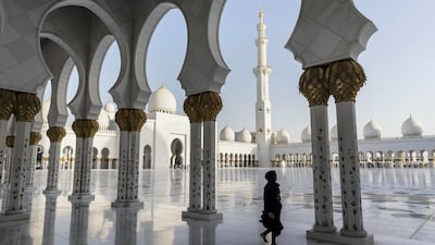 A visitor walks along the arched walkways at Sheikh Zayed Grand Mosque in December 2017. Antonie Robertson / The National