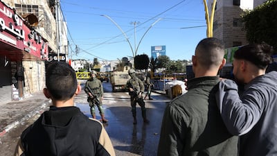 Palestinians watch patrolling Israeli soldiers as the military closes part of the H2 southern sector of Hebron. AFP