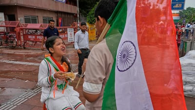 An Indian schoolgirl eats noodles and her brother carries an Indian flag as they return from school after an Independence Day celebration in New Delhi. AP