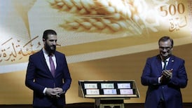 Syria's President Ahmad Al Shara and central bank chief Abdulkader Husrieh stand next to the country's revamped currency notes at the Conference Palace in the capital Damascus. AFP