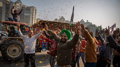 Indian farmers are showered with flower petals while leaving their protest site in Singhu, on the outskirts of New Delhi, on Saturday. AP