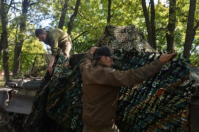 Ukrainian service members cover a tank with a camouflage net during the early stages of Russia's invasion of Ukraine last year. Reuters