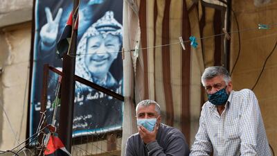 Palestinians wearing masks to help curb the spread of the coronavirus stand on their balcony watching the arrival of the Lebanese health minister at Jalil, or Galilee Palestinian refugee camp, in Baalbek. AP