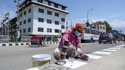 A migrant labourer paints white road markings on the International Labour Day in Srinagar. AFP