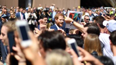 Prince Harry smiles as he meets people outside the Sydney Opera House. AFP