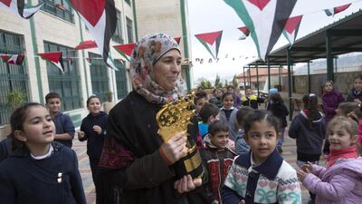 Hanan Al Hroub shows her Global Teacher trophy to Samiha Khalil students on March 20, 2016. The mother of five grew up in a refugee camp near Bethlehem. Heidi Levine for The National