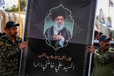 Members of Iraq's Popular Mobilisation Forces carry a banner depicting Iran's late supreme leader Ayatollah Ali Khamenei. AFP