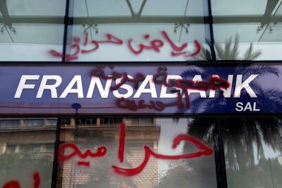 Bank customers write Arabic words thats read "Riad is a thief. Thieves" (Riad Salameh, the governor of Lebanon's Central Bank) on a facade of bank in Beirut, Lebanon, in November 2021. AP