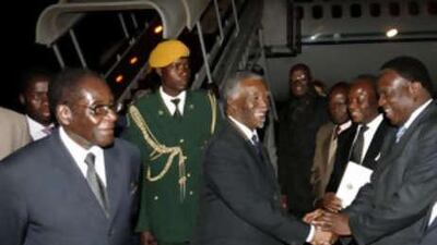 The South African president Thabo Mbeki greets government officials next to the Zimbabwe president Robert Mugabe (left) at Harare International airport.