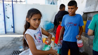Palestinian children in Khan Younis fill bottles with water from public taps during the conflict with Israel. Reuters