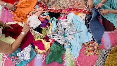 Volunteers of Save Scrap and Sew sort out the collected fabric. Reem Mohammed / The National