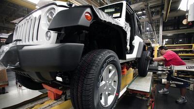 A worker installs tires on a 2014 Jeep Wrangler as it undergoes assembly at the Chrysler Toledo North Assembly Plant. Bill Pugliano / Getty Images / AFP