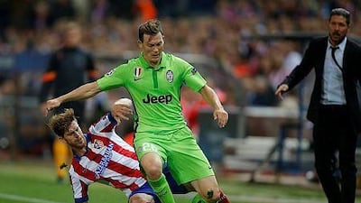 Juventus' Stephan Lichtsteiner, centre, is tackled by Atletico's Cristian Ansaldi as Atletico's coach Diego Simeone watches during the Group A Champions League soccer match at the Vicente Calderon stadium in Madrid, Spain, on October 1, 2014. (AP Photo/Andres Kudacki)