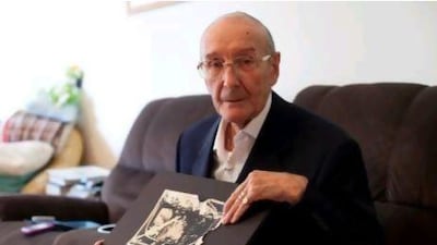 Charles Henry Wilson with the photograph he took on his first assignment as a British Army photographer: the Queen passing by after her coronation in 1953.