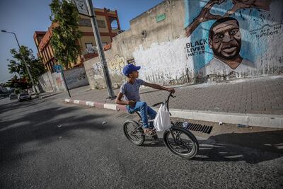 A Palestinian boy rides his bicycle next a mural of George Floyd, who died in Minneapolis police custody, in Gaza City. EPA