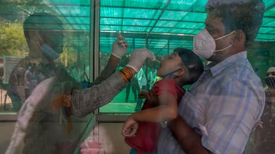 A health worker takes a swab sample of a child to test for Covid-19 at a government hospital in Noida, a suburb of New Delhi, India. AP Photo