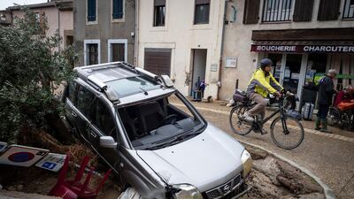 A man rides past a damaged car in the town of Villegailhenc. AP Photo