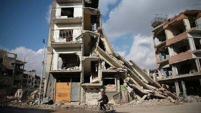 A man cycles past damaged buildings in the rebel-held city of Douma on December 30, 2016, the first day of a fresh ceasefire in Syria. Bassam Khabieh / Reuters