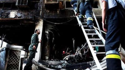 Firemen and police officials examine the scene of the fire on Airport Road in Abu Dhabi.
