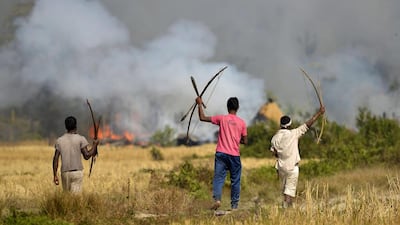 Tribal men watch houses belonging to Bodo community after they were set on fire on December 24, 2014, in retaliation for attacks by Bodo rebels a day earlier. EPA