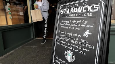 A customer wearing a face mask takes out a drink from a Starbucks coffee shop in Seattle. Global coffee demand is set to fall for the first time since 2011 as demand from the out-of-home market, which accounts for 25 per cent of sales, withered during lockdown measures to control the Covid-19 pandemic. AP Photo