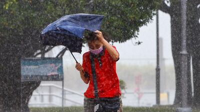 A woman shelters under an umbrella from heavy rain after local governments across Taiwan suspended work and schools to brace for Typhoon Gaemi in New Taipei. EPA