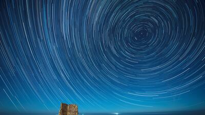 An overlay image of 128 photographs shows circumpolar star trails over San Telmo tower in Ubiarco, Cantabria, Spain, during the Gemenids meteor shower. EPA
