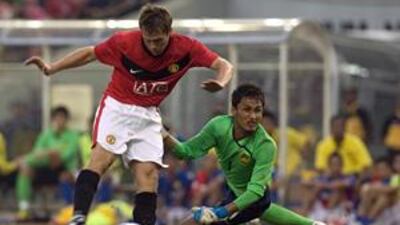 New signing Michael Owen beats goalkeeper Mohd Farizal Marlias to score the winning goal for Manchester United against a Malaysian X1 in Kuala Lumpur on Saturday.