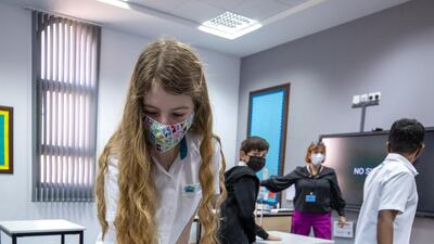 A pupil disinfects her desk before the class.