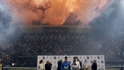 Federer and Djokovic pose with their Dubai Duty Free Tennis Championships trophies as fireworks go off in the background. Karim Sahib / AFP