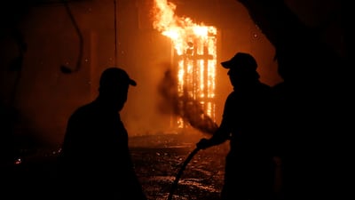 People try to extinguish a burning house during a wildfire in the Nea Kifisia suburb north of Athens.