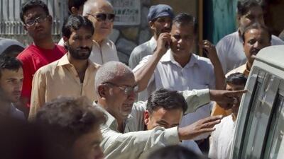 A brother of the Pakistani prosecutor Chaudhry Zulfikar, centre, wearing glasses, mourns next to an ambulance carrying his brother's body outside his residence in Islamabadon Friday. Anjum Naveed / AP Photo