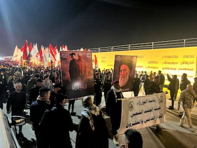 People hold photos of Abu Mahdi Al Muhandis, deputy commander of the Popular Mobilisation Forces, and Iranian general Qassem Suleimani in Baghdad, on Monday. AP