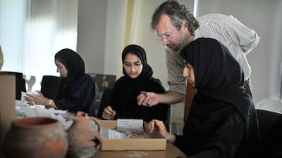 Dunia Al Blooshi, left, Afra Al Nuaimi and Shamsa Al Dhaheri assess pottery finds from Saadiyat in their Emirati Studies class at Zayed University under the tutelage of Dr Timothy Power, an archaeologist and assistant professor at the university. Delores Johnson / The National