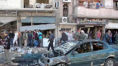 Syrians inspect the site of a car bomb explosion in the central city of Homs. Sana via AFP