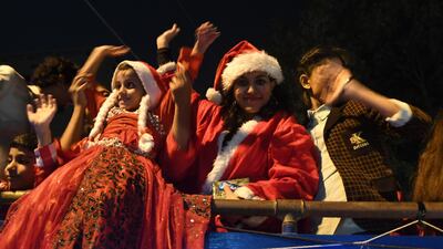 Girls wearing Santa costumes wave from a bus on a street in Karachi, as part of the Christmas celebrations. AFP