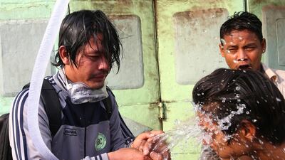 People rinse their faces with water after tear gas was used to disperse a protest in Mandalay, Myanmar. AP