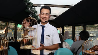 Jonald Jeff Sarmiento serves food to guests during the afternoon tea on a BusTronomy experience in Dubai. Pawan Singh / The National