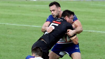 Dubai Exiles's DuRandt Gerber, in black, is tackled during the Gulf Men's final against Jebel Ali Dragons at the Dubai Rugby Sevens. Satish Kumar for The National