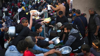 Displaced Palestinians in Rafah collect food donated by a charity before iftar on the first day of Ramadan. AFP