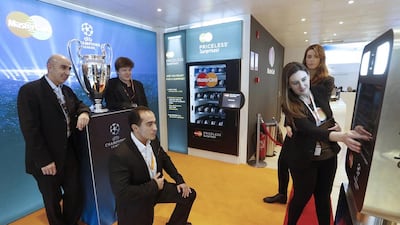 Visitors to the MasterCard booth take a photo with the UEFA Champions League trophy at the Mobile World Congress. Marce Martinez / AP Images for MasterCard