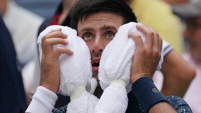 Novak Djokovic towels off in the heat against Marton Fucsovics. AFP